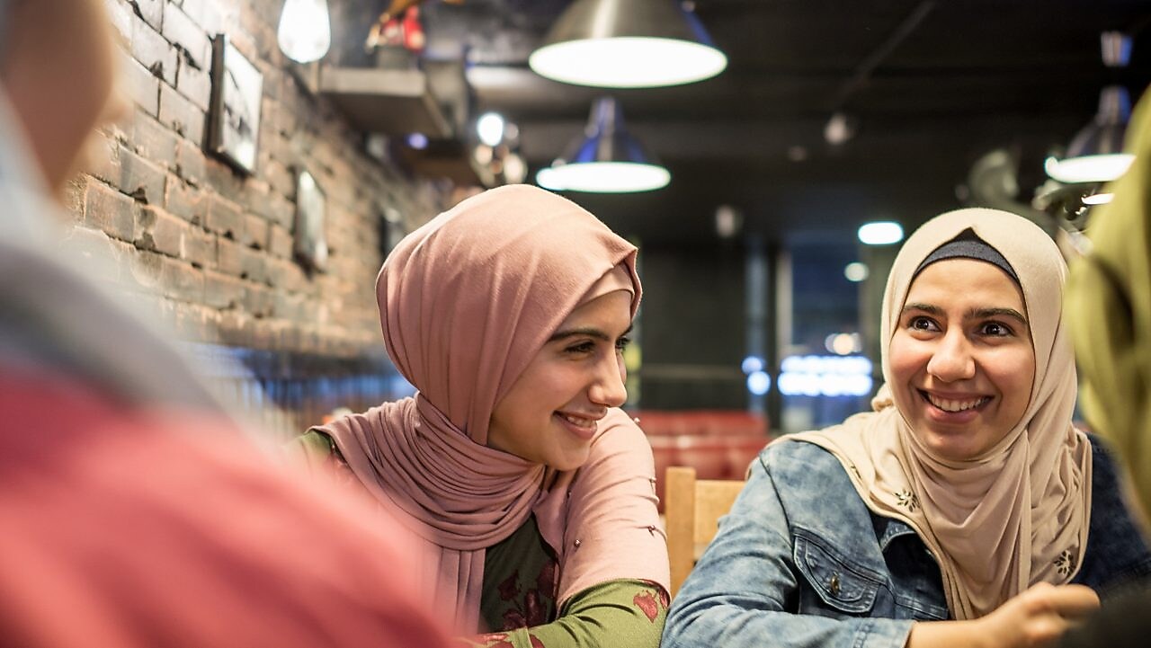 Dos mujeres sentadas en una mesa sonriendo