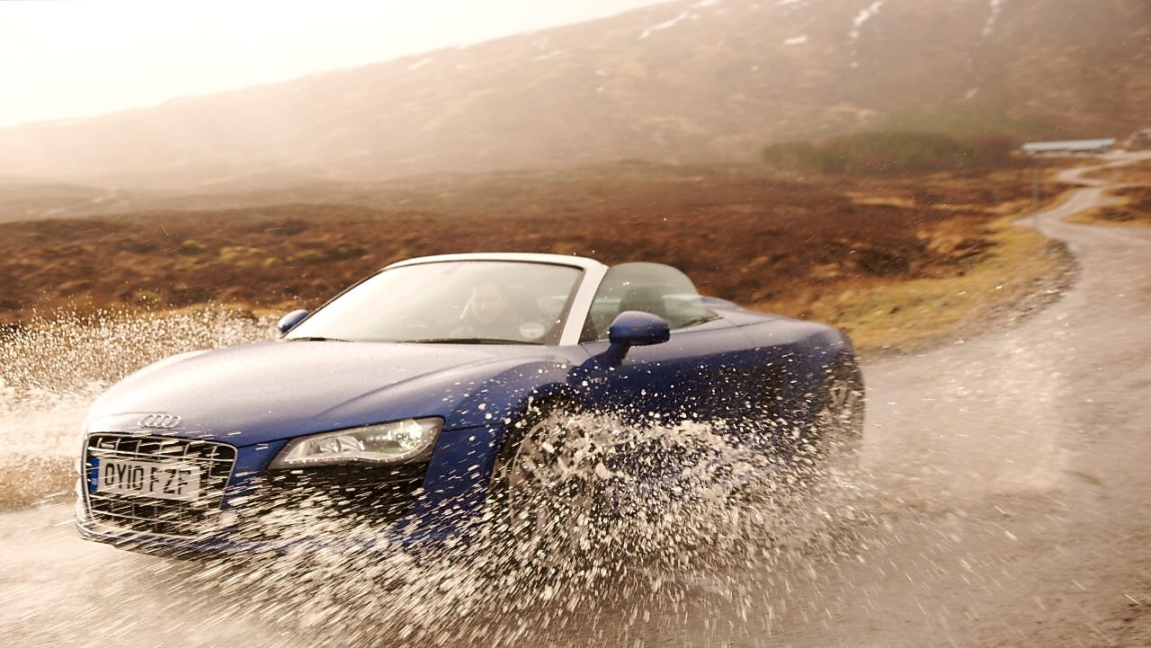 Hombre conduciendo un auto a través de un gran charco de agua