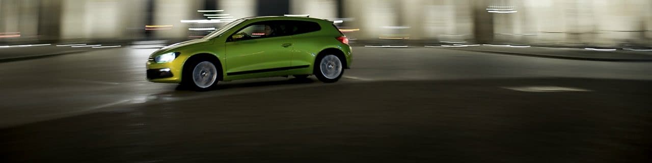 Auto verde conduciendo velozmente de noche