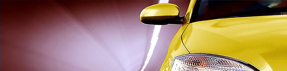 Parte frontal de un auto amarillo circulando por un túnel, con vista del faro delantero y el espejo lateral derechos