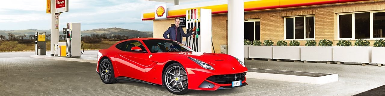 Ferrari rojo en una estación de servicio Shell con un hombre apoyado sobre un surtidor