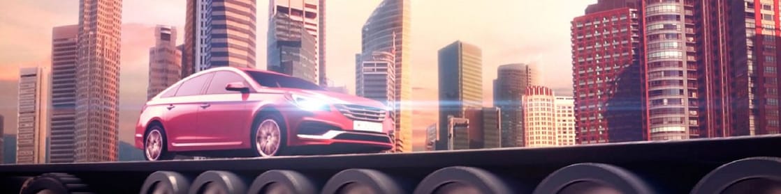 Auto rojo circulando con los faros encendidos con el horizonte de la ciudad al fondo
